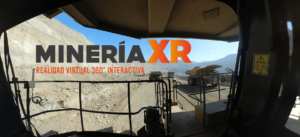 La fotografía está tomada desde la parte delantera de una excavadora. Se observan múltiples barras de hierro de seguridad y una escalera. A lo lejos, se observa un entorno rocoso y con gravas. Hay además dos máquinas de excavación amarillas con ruedas grandes